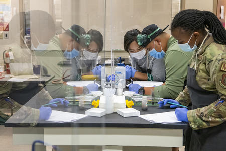 Three students stand at a lab table