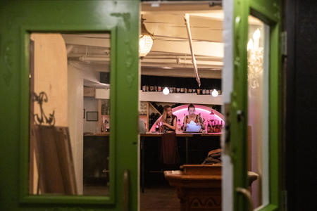 A green door is open to the Rabbit Hole, showing two workers behind a counter. 
