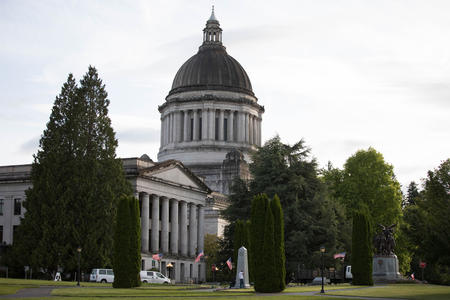 Trees flank the grey and white dome of the state Legislative Building in Olympia