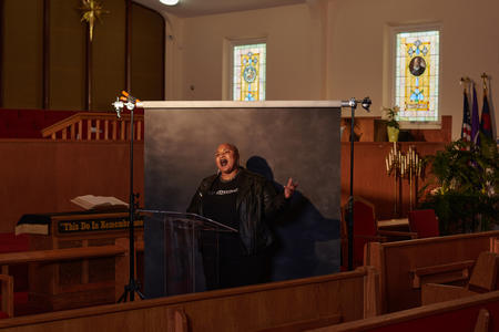 a person standing in front of a gray backdrop in a church