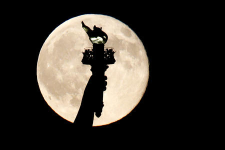Statue of Liberty torch in front of full moon