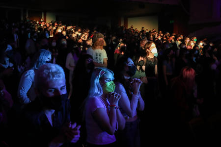 Person in mask bathing in blue light among larger audience