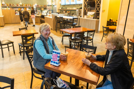 Two women sitting at a table in mall cafe 
