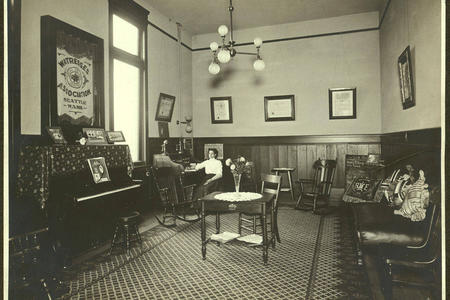 Alice Lord in her desk in the Waitresses Association of Seattle offices. The union's banner hangs over a piano to the left. 
