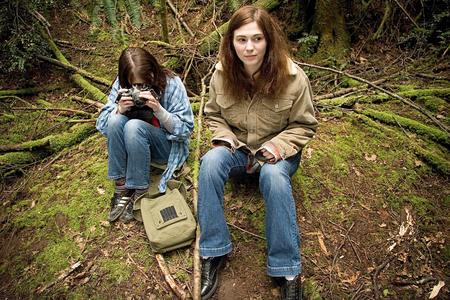 two young women sitting next to each other on mossy ground