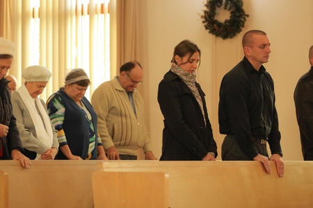 people stand and pray in church pews