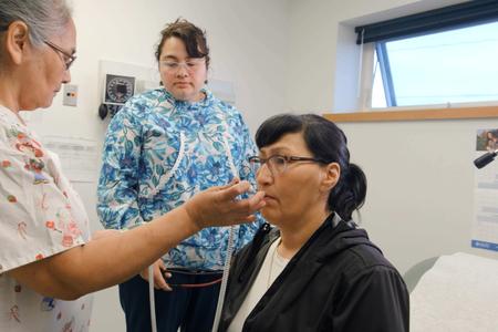 Two health aides work with a patient in Alaska care clinic