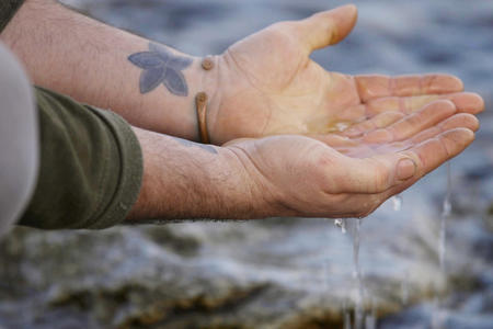 Hands filled with water on shore