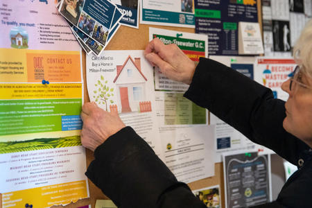 Woman placing flyer on a wall with other flyers