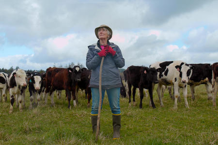 a woman standing with cows behind her