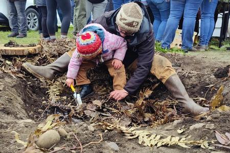 Sam Barr works with his young daughter, Seli to dig a cooking pit