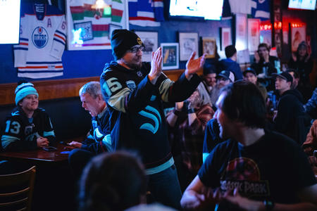 A fan stands in a Kraken jersey in a bar