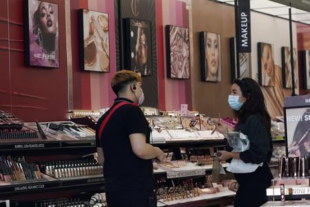 A worker, at left, tends to a customer at a cosmetics shop