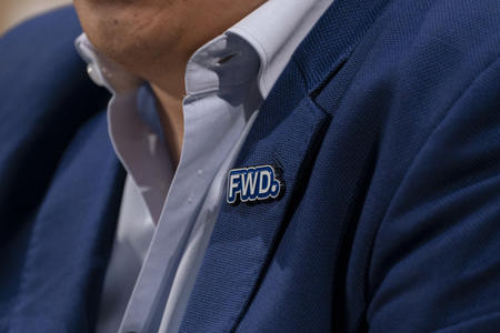 A pin reading “FWD.” on the lapel of a blue blazer