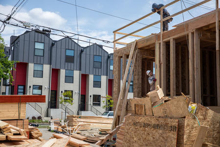 construction workers on a jobsite with completed townhomes in the background