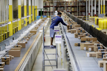 An Amazon worker fixes boxes on a conveyor belt