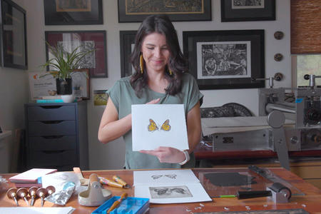 Printmaker Christie Tirado displays a print of Monarch butterflies.