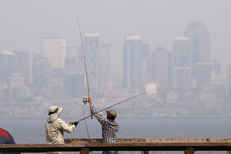 A pair of anglers uncross their lines while fishing with a city skyline in the background