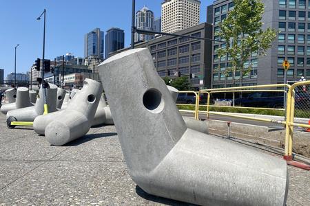a series of concrete sculptures shaped like jacks with a city skyline behind