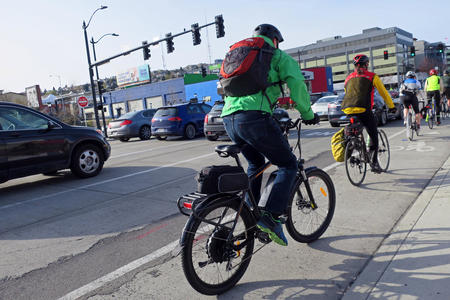 People ride e-bikes in a bike lane on a Seattle street.