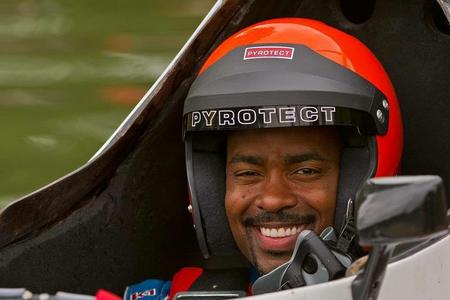Brent Hall smiles underneath a helmet in his racecar. 
