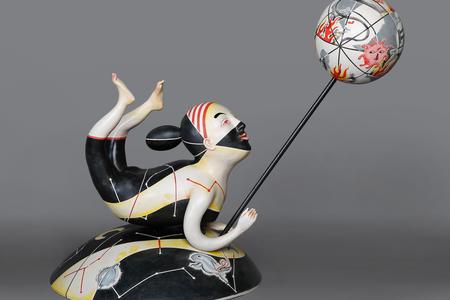 a ceramic figure of a humanoid figure painted black and white holding a burning globe on a stick