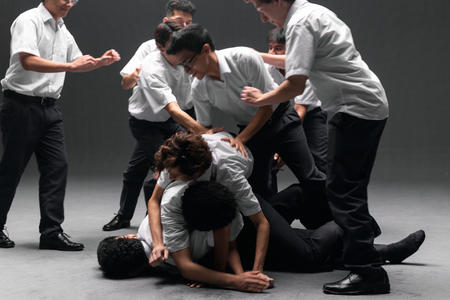 a photo of several boys in school uniforms, rough housing and piling on top of each other
