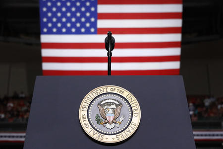 A podium with a President of the United States seal is pictured in front of an American flag 