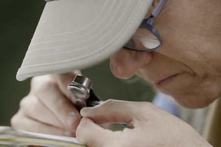 close up of woman looking through tiny magnifying glass