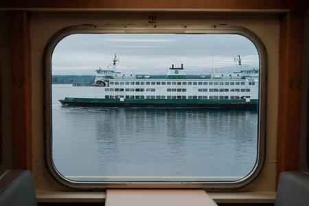 A ferry on Puget Sound is seen through the window of another ferry.