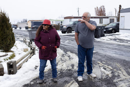 A man and woman are pictured walking through Moxie Community, a mobile home park in Moxee, Washington.