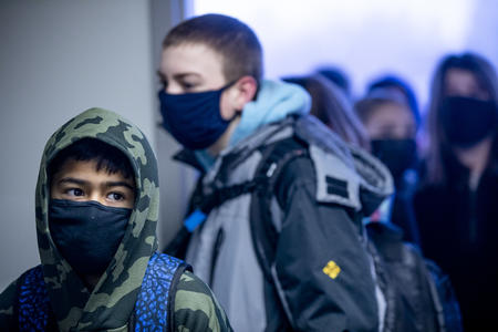 Two students wearing masks are looking away from the camera