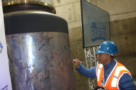 Hanford engineer Waheed Abdul signs the first canister to contain melted glass at Hanford in December 2023.
